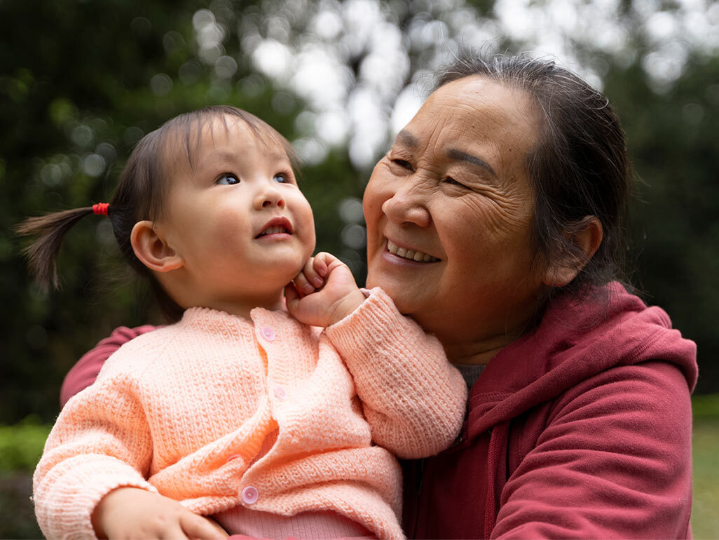 A woman smiling at and holding a baby